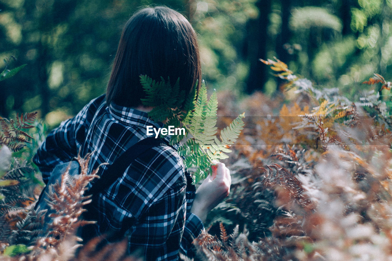 REAR VIEW OF PERSON STANDING BY PLANTS IN FOREST