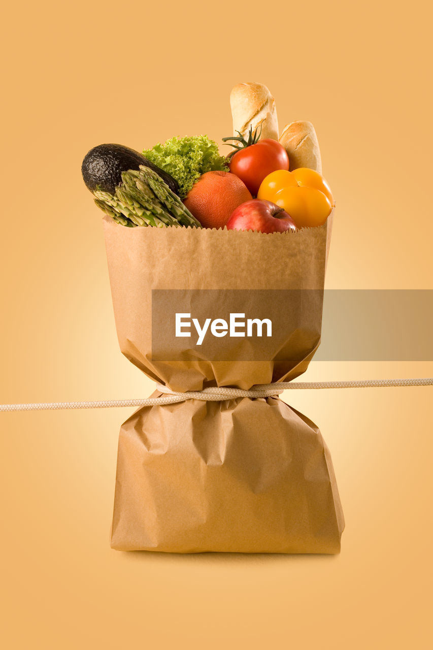 Close-up of tied up vegetables against yellow background