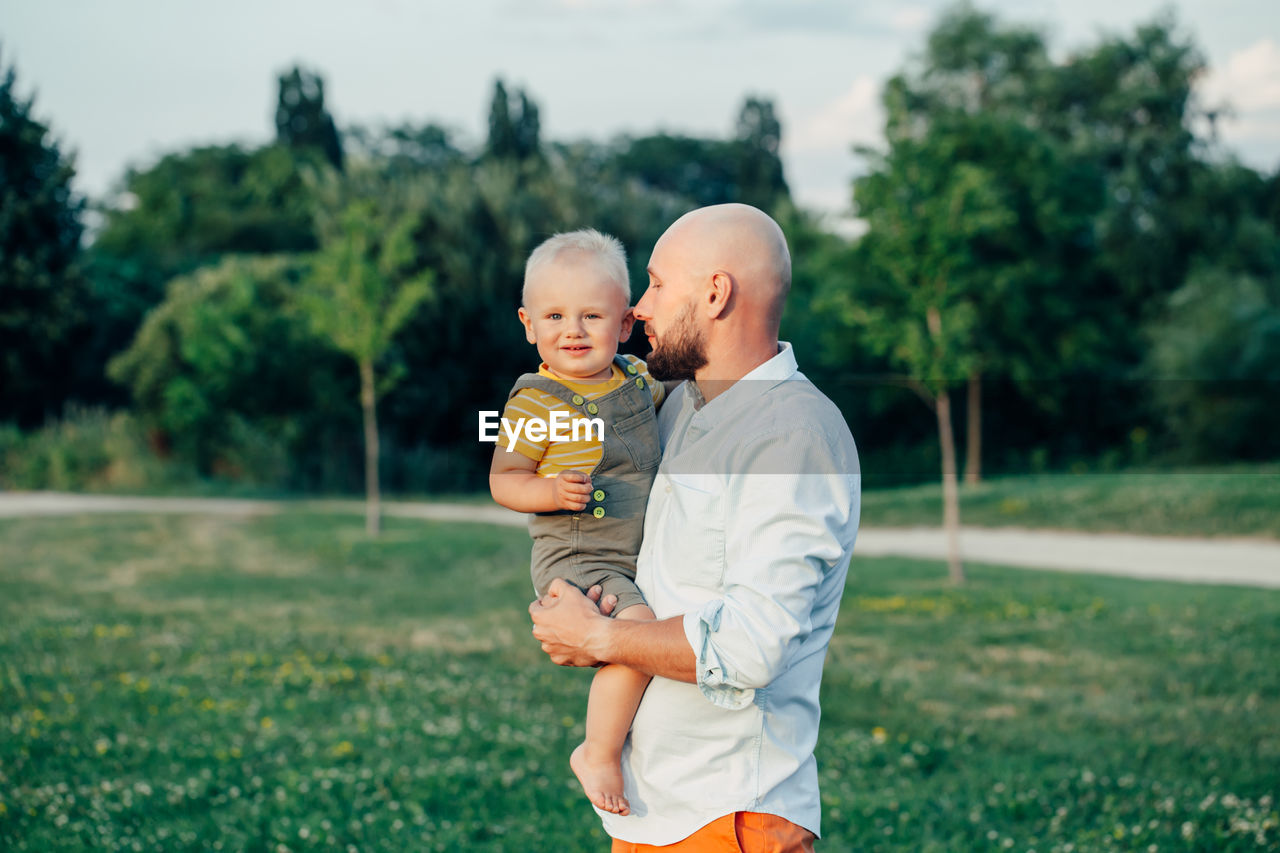 Father standing with son against plants at park