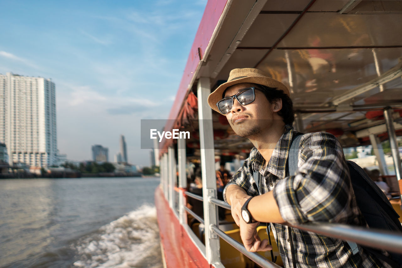 Tourist wearing hat standing in boat on river