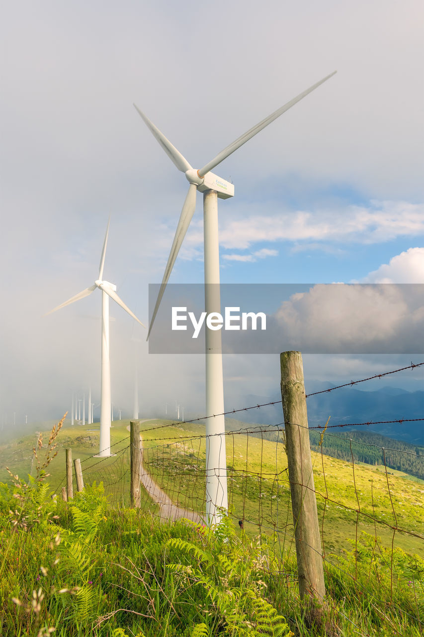 WINDMILLS ON LANDSCAPE AGAINST SKY