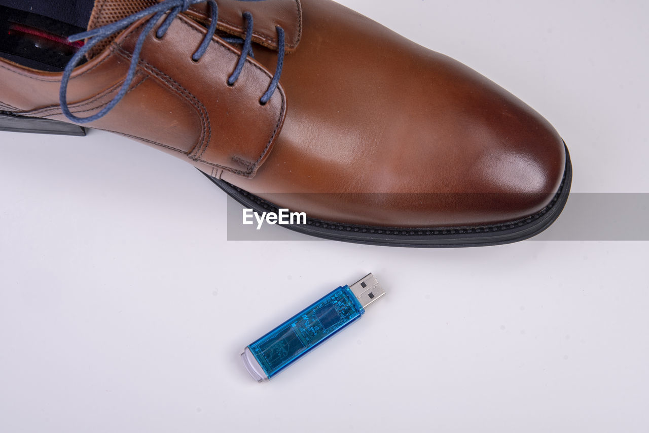 High angle view of usb stick and shoe over white background