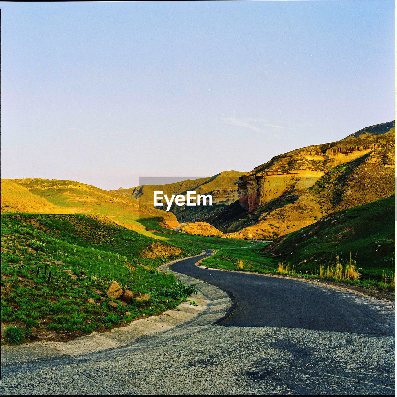 Road leading towards mountains against clear sky