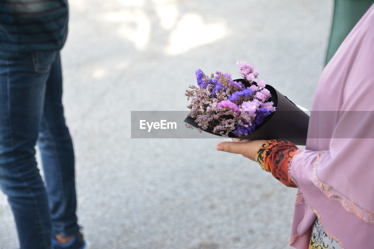 MIDSECTION OF WOMAN HOLDING BOUQUET OF PURPLE FLOWER