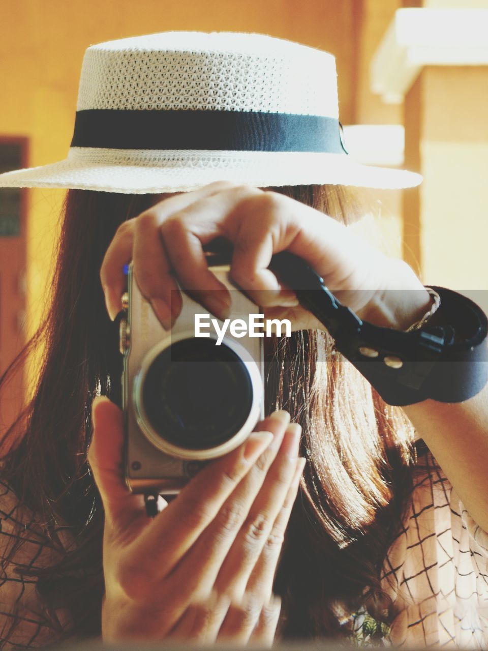 Close-up of woman photographing while reflecting in mirror