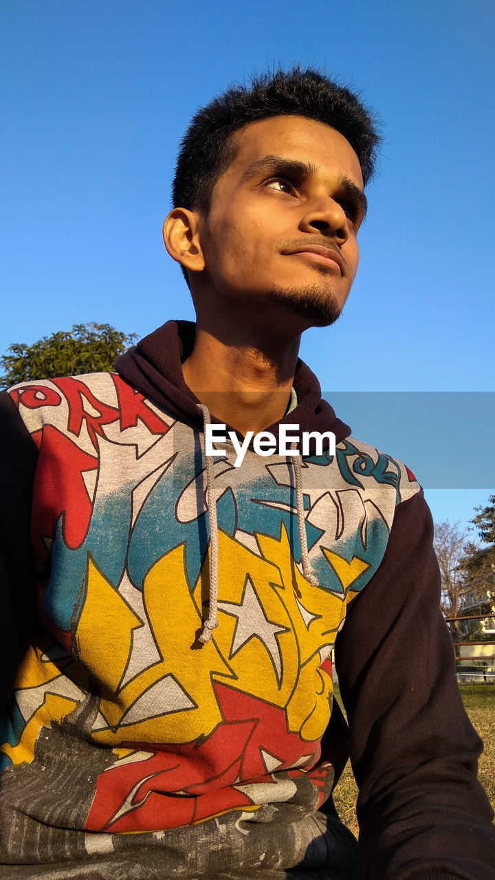 Man looking away against clear blue sky