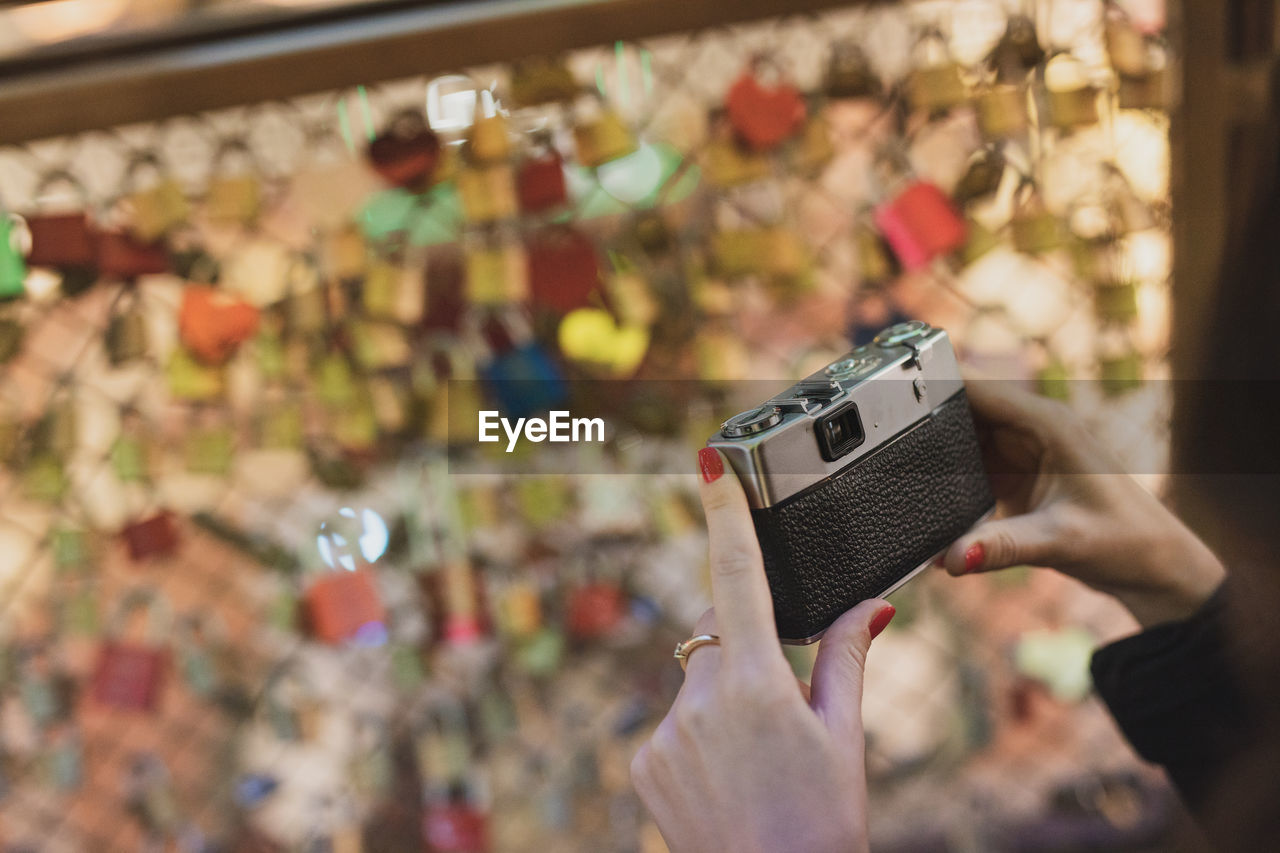 Close-up of hand holding camera against glass ceiling