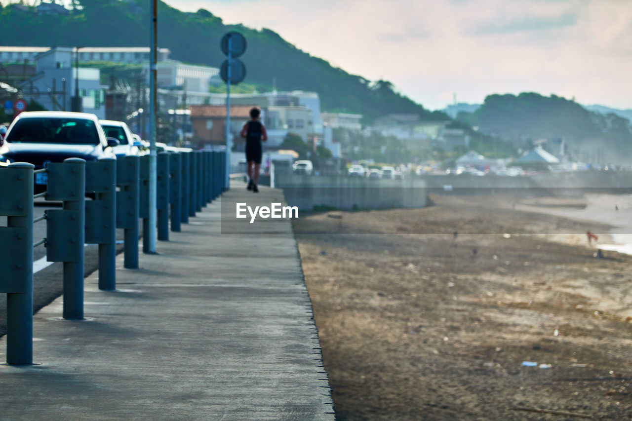 Rear view of man running on road by the beach  against sky