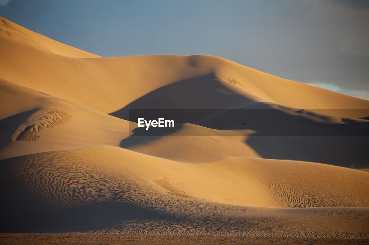 Sand dunes against sky during sunset