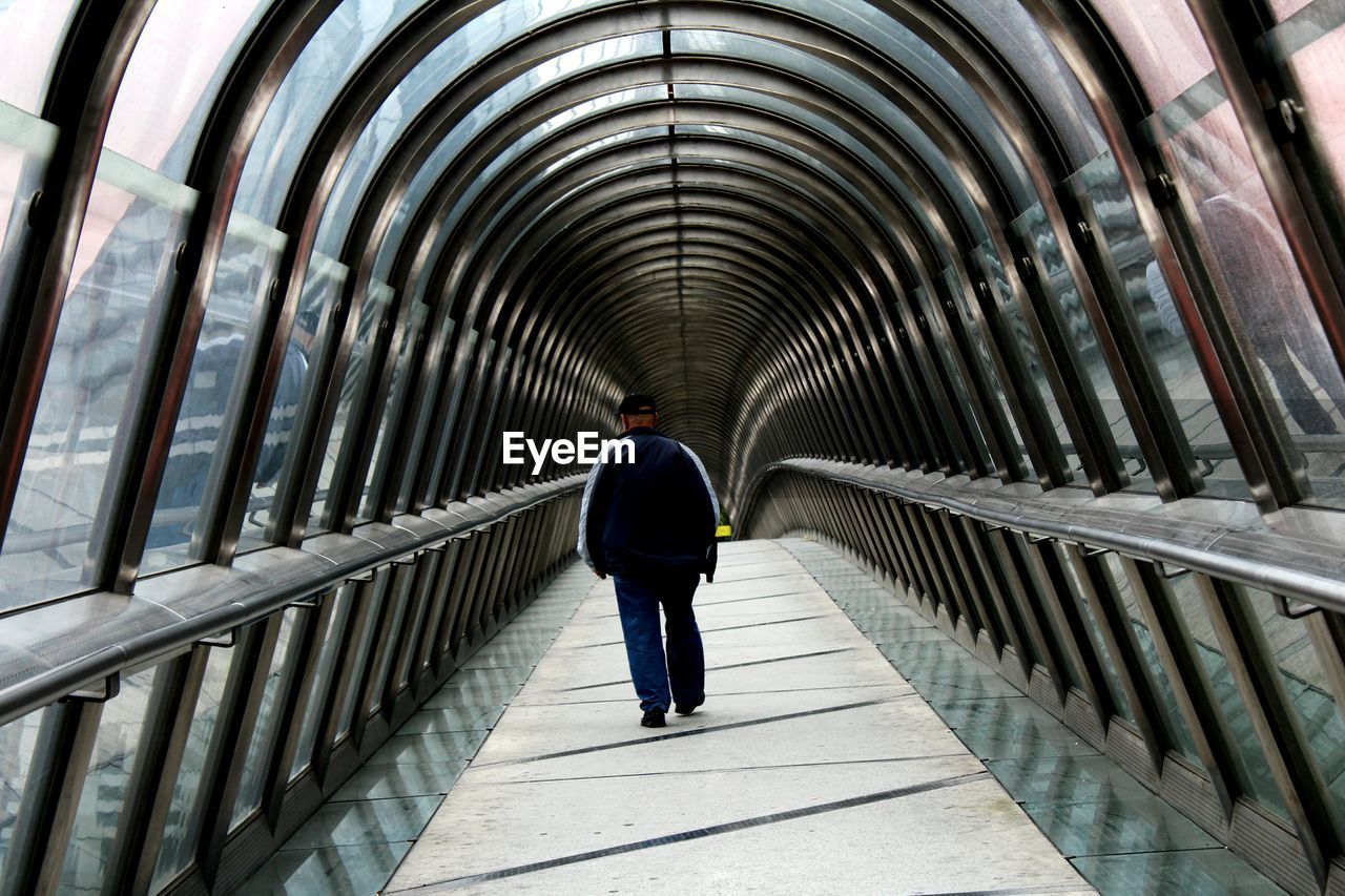 Rear view full length of man walking in covered footbridge