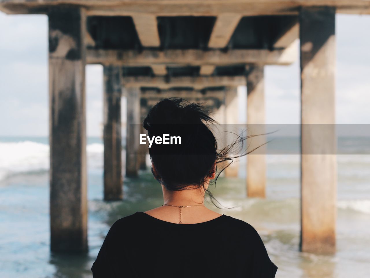 Rear view of woman under pier