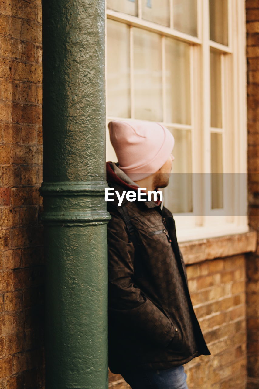 Side view of woman standing against wall