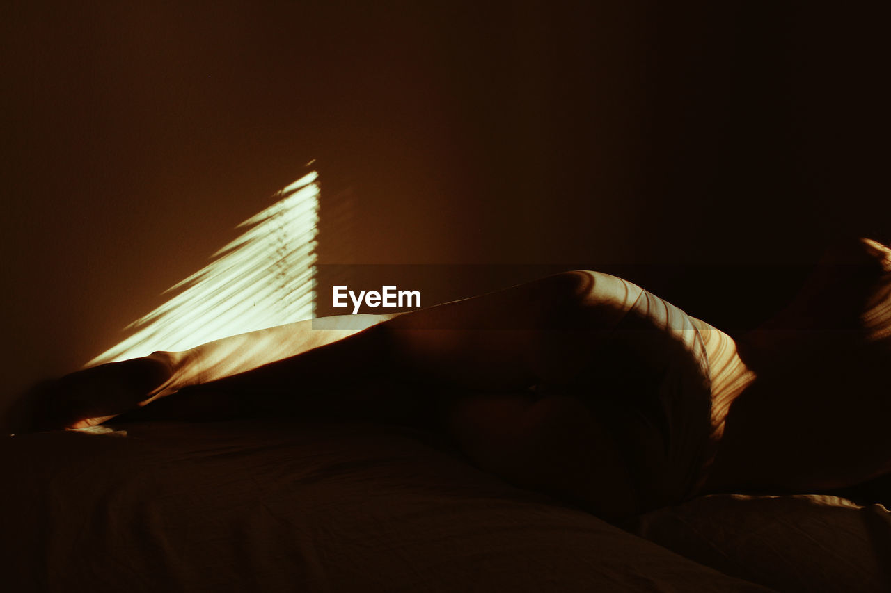 CLOSE-UP OF SUNLIGHT FALLING ON WOMAN LYING DOWN IN BED
