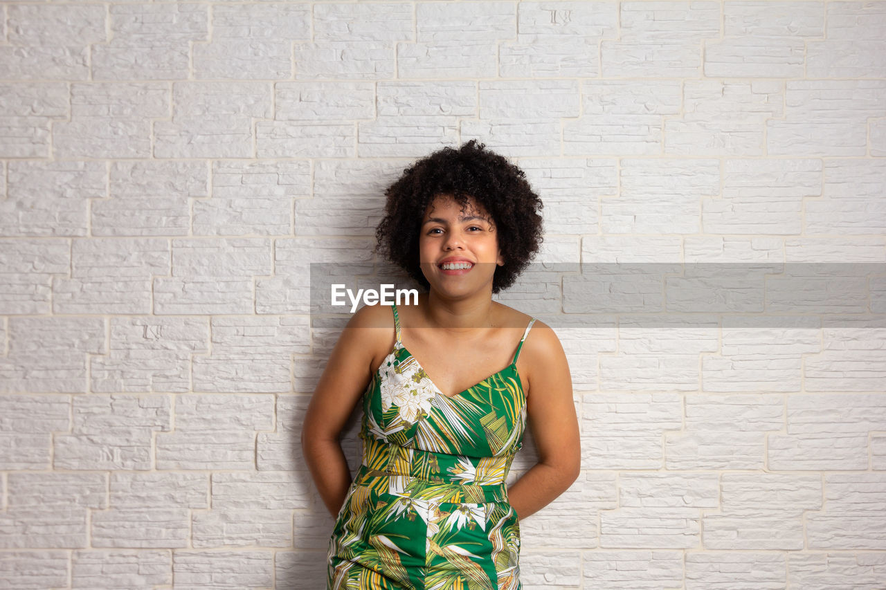 portrait of smiling young woman standing against wall