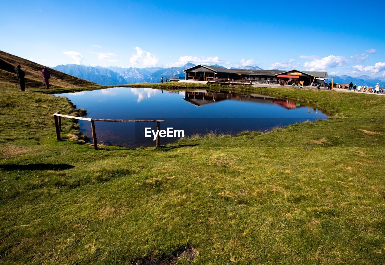 Built structure on field by lake against sky