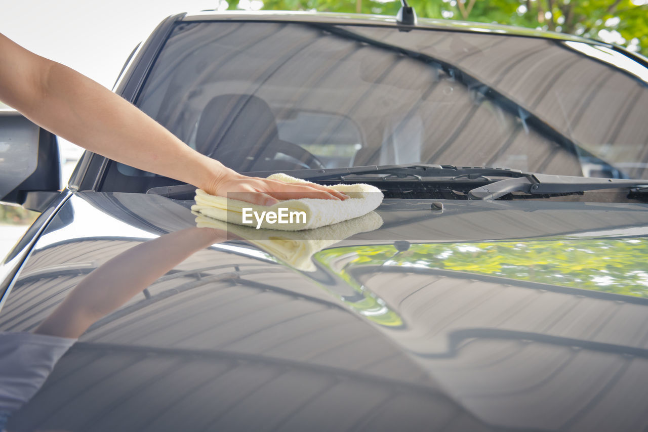 LOW SECTION OF PERSON HOLDING UMBRELLA AGAINST CAR