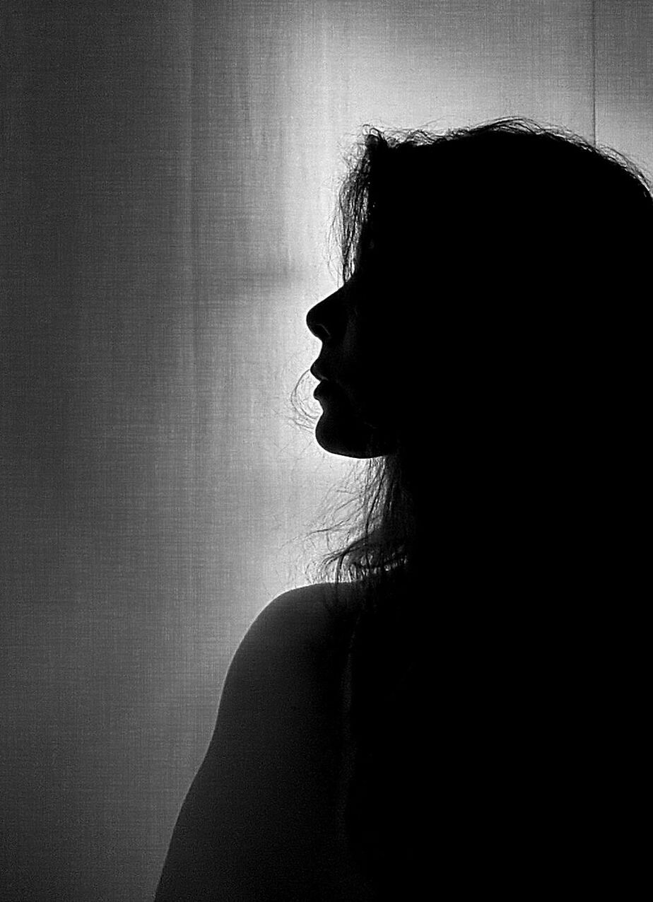 Silhouette woman standing in front of curtain