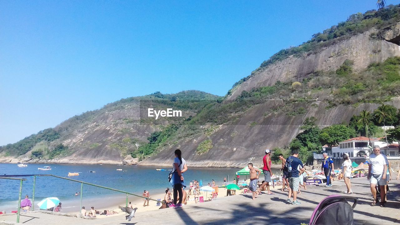 PEOPLE AT BEACH AGAINST BLUE SKY