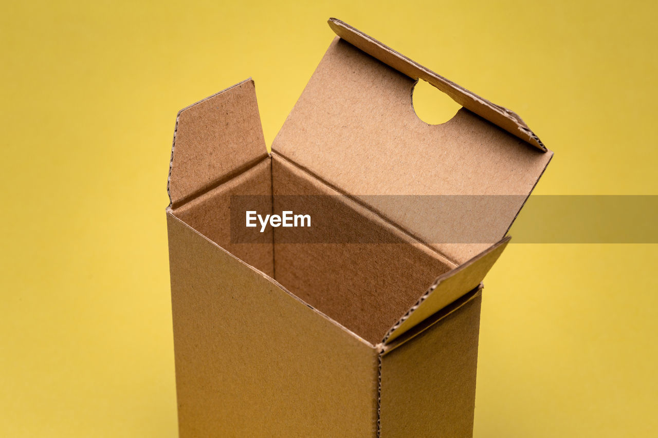 High angle view of cardboard box on yellow background