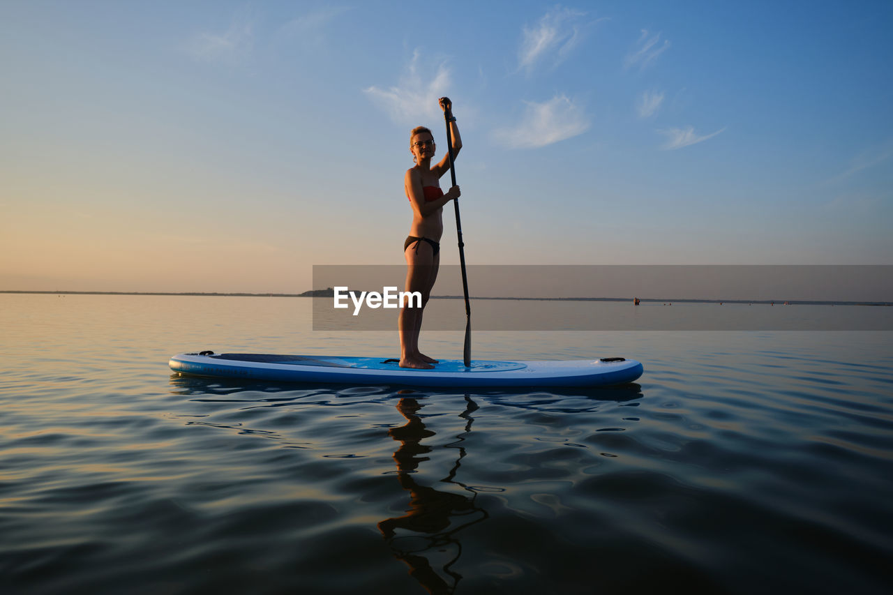 Full length of woman paddleboarding in sea