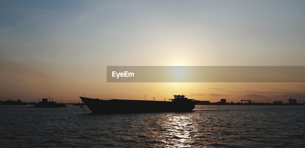 Silhouette ship in sea against sky during sunset