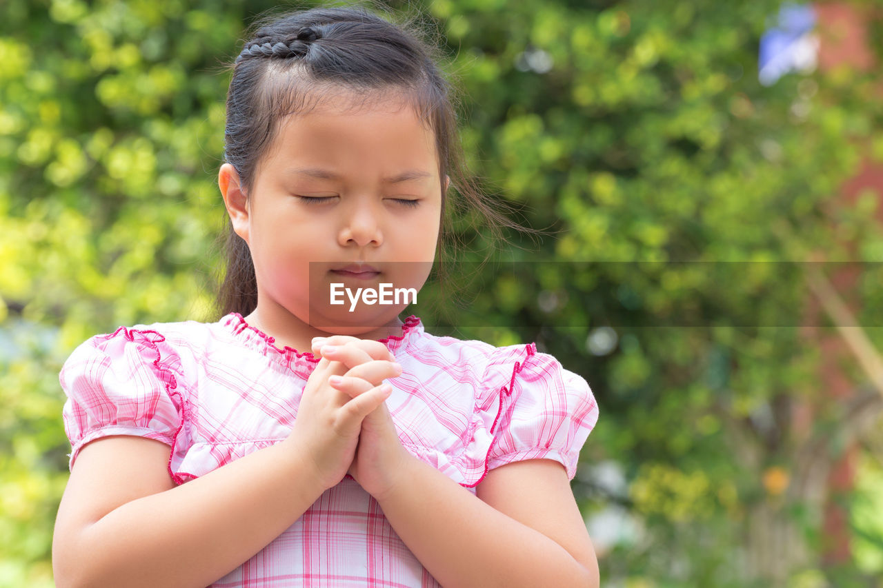 Close-up of girl praying while standing outdoors