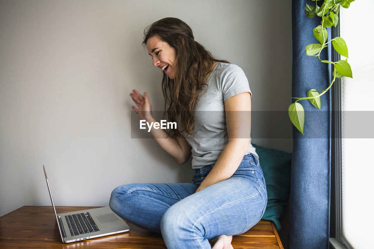 Smiling portrait of individual woman facetiming on laptop from home
