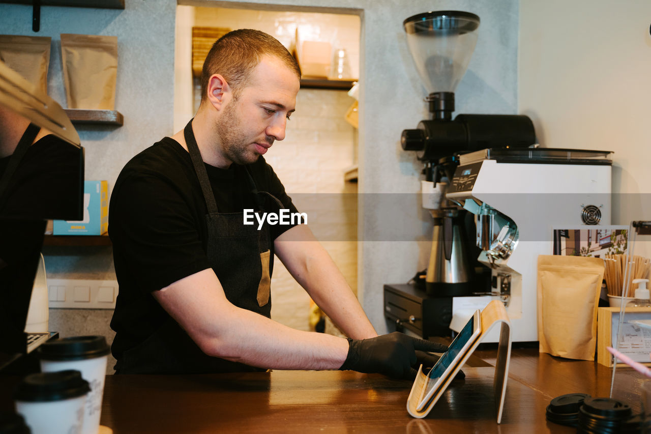 Waiter holding a tablet in hand while working in a coffee shop