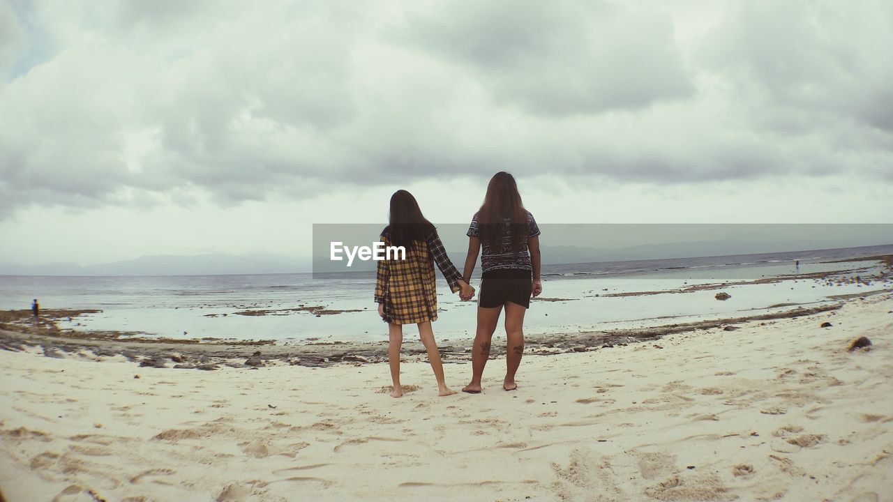 Rear view of women on beach against sky