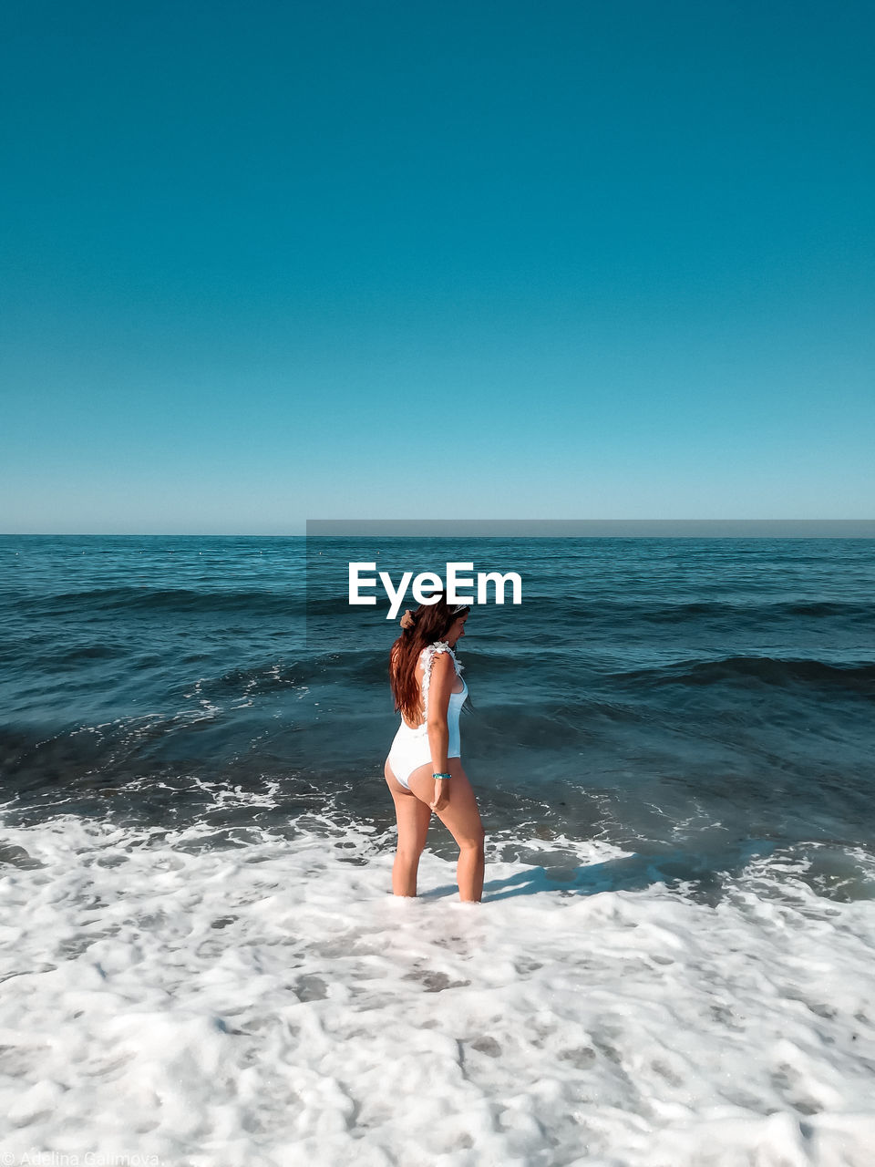 Woman standing in sea against clear sky