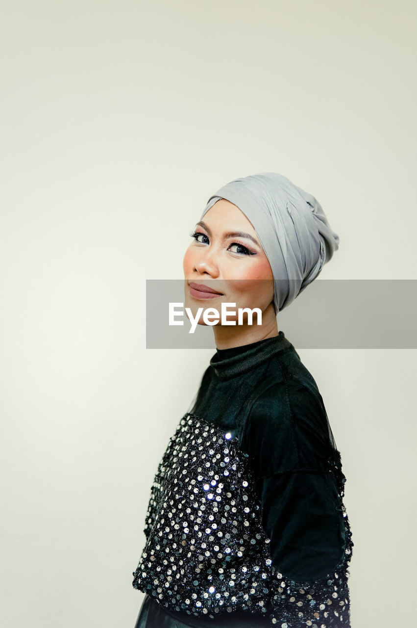 Portrait of smiling woman standing against white background