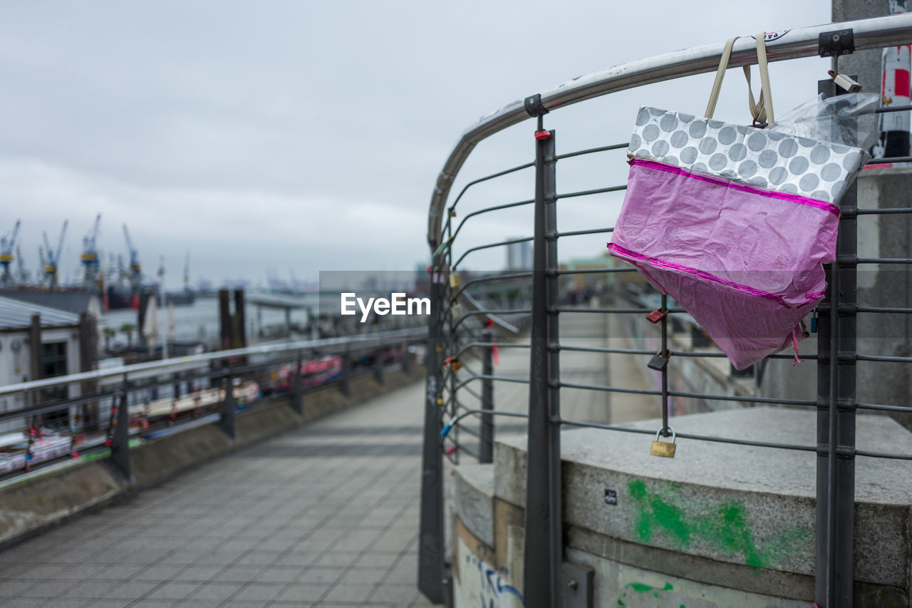 Close-up of bag hanging on railing against sky