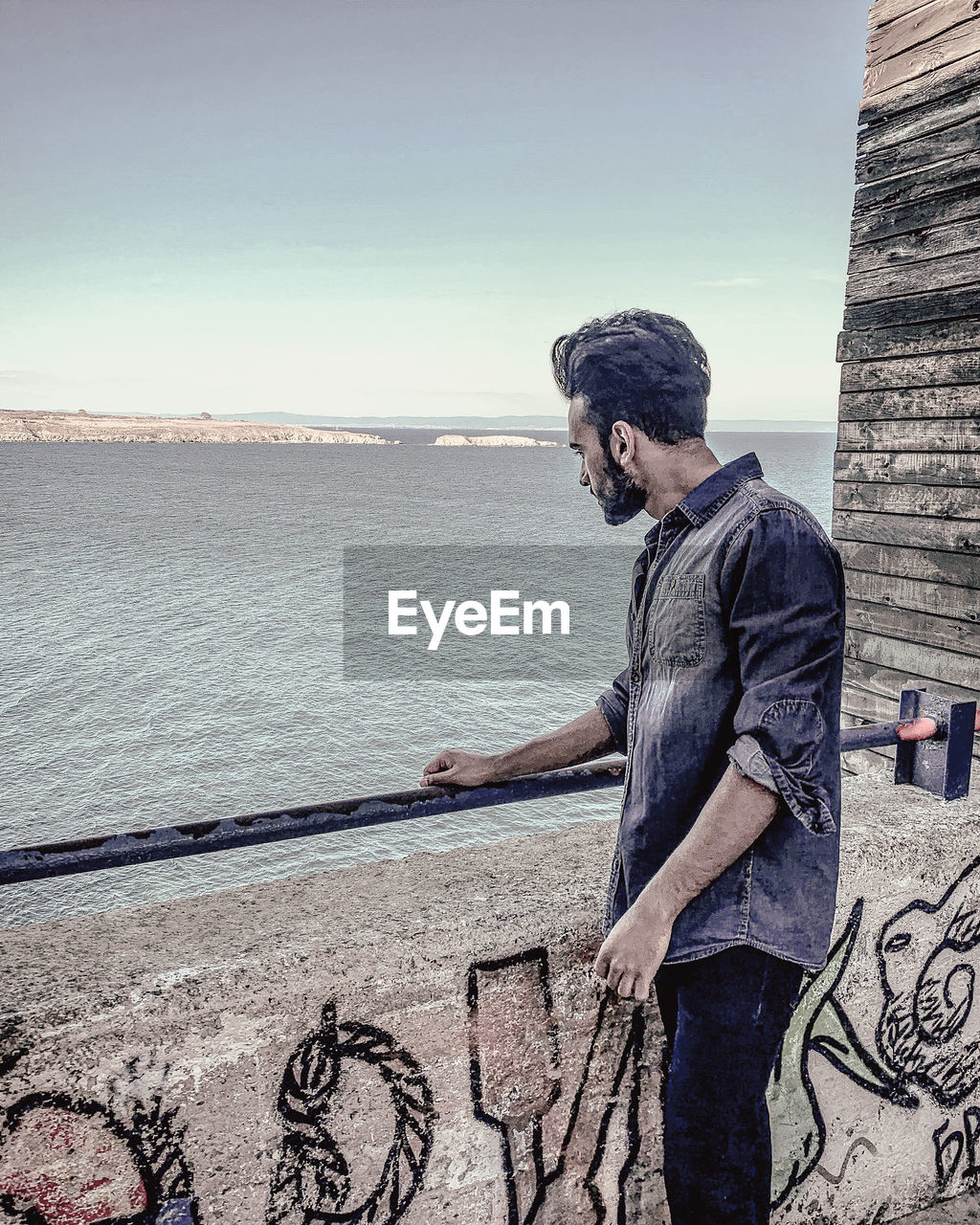 Side view of young man standing against sea