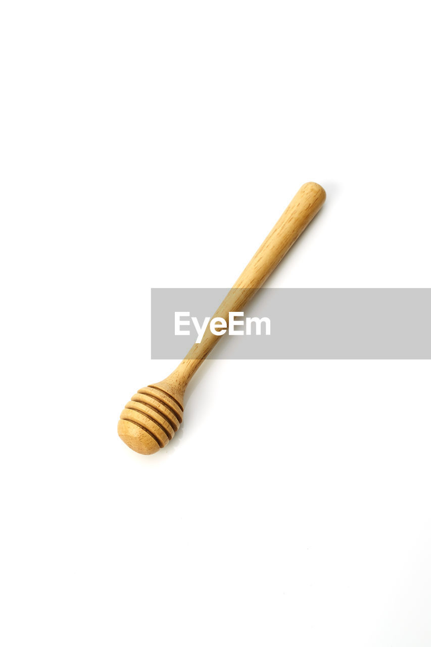 High angle view of wooden honey dipper over white background