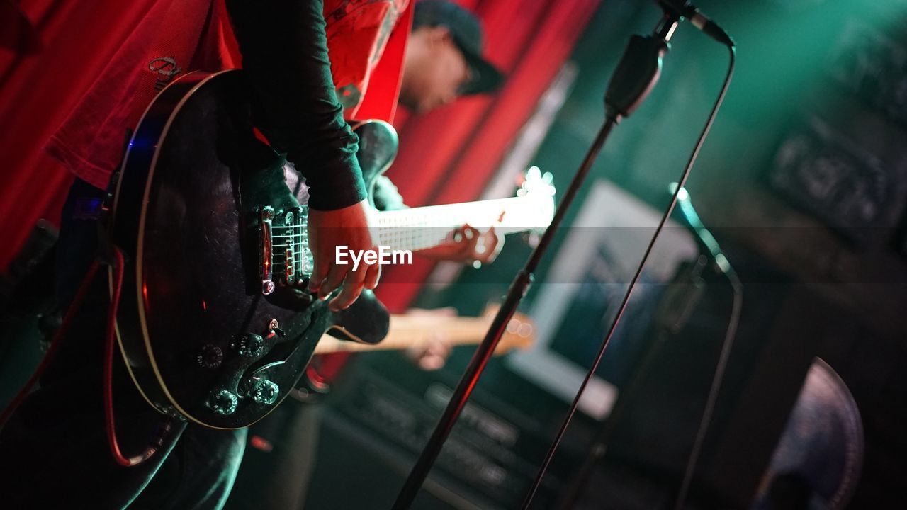 Midsection of man playing guitar on stage