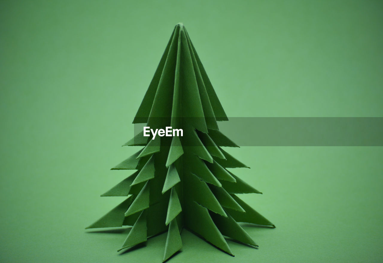 Green origami christmas tree on a green background.