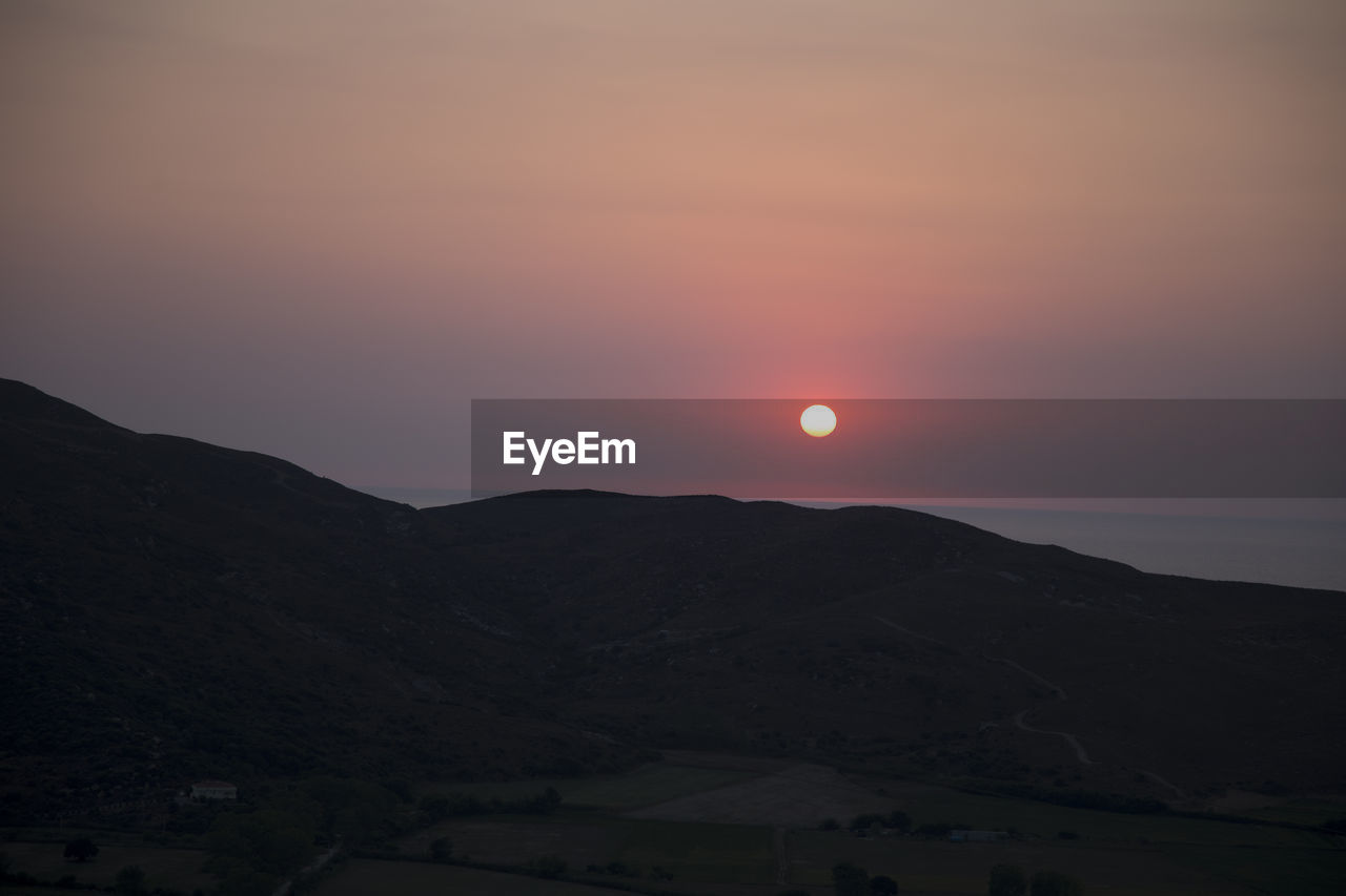 SCENIC VIEW OF SILHOUETTE MOUNTAINS AGAINST ORANGE SKY