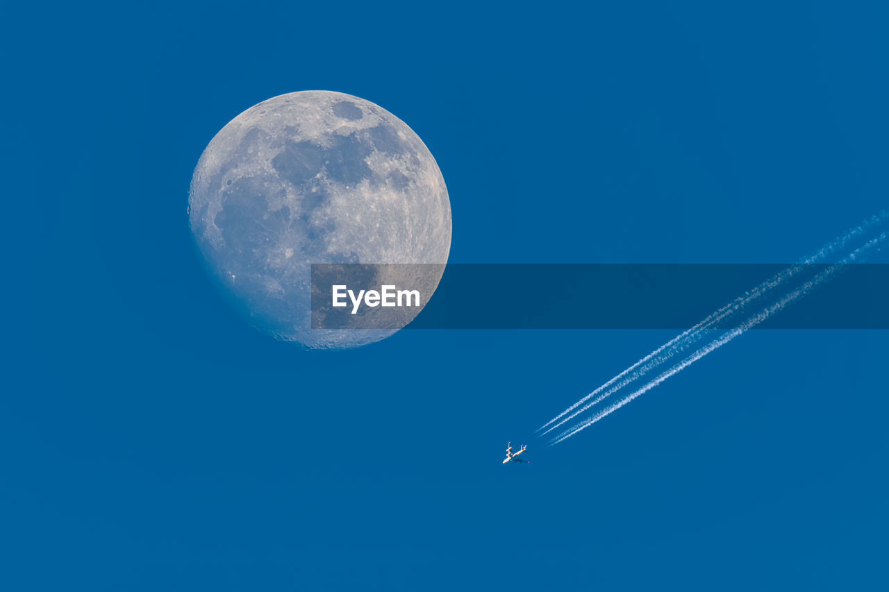 Full moon and flying plane with blue sky.