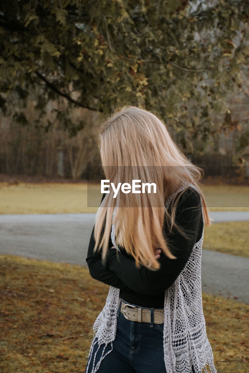 Woman with blond hair standing in park during autumn