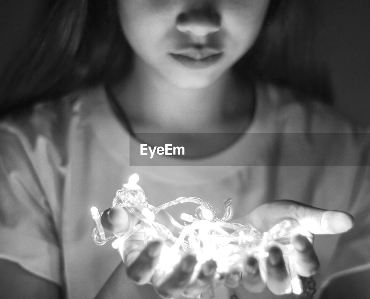 Midsection of woman holding illuminated string lights at home