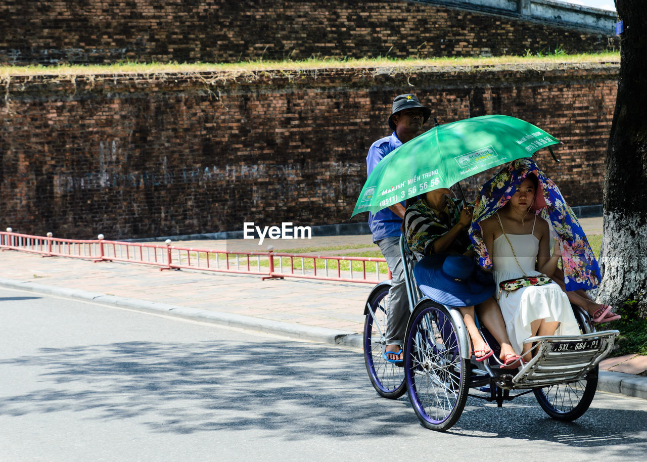 REAR VIEW OF MAN RIDING BICYCLE ON ROAD