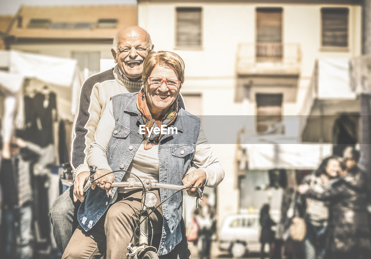 Portrait of senior couple on bicycle at street in city