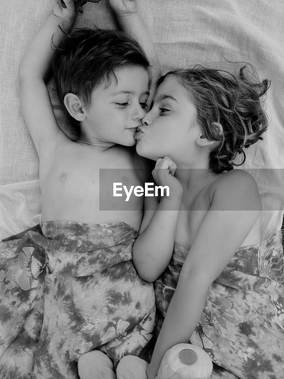 Siblings kissing while lying on bed
