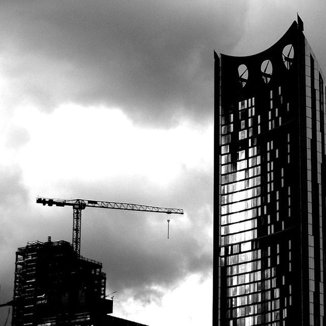 LOW ANGLE VIEW OF CRANE AND CRANE AGAINST CLOUDY SKY