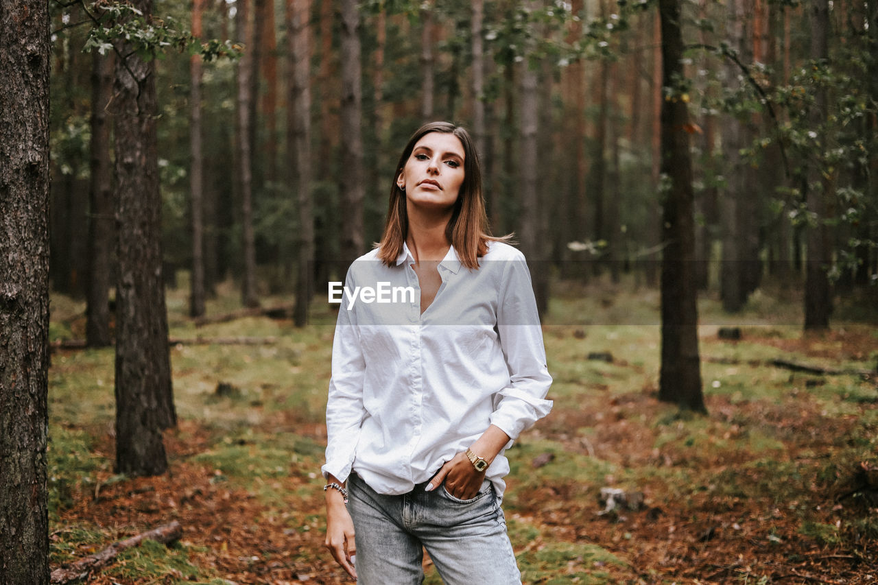 Mid adult man standing against trees in forest