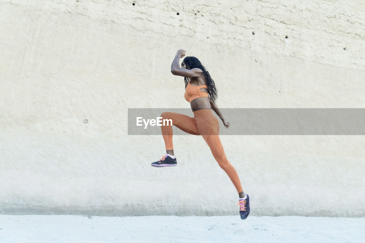 Side view of woman running on wall