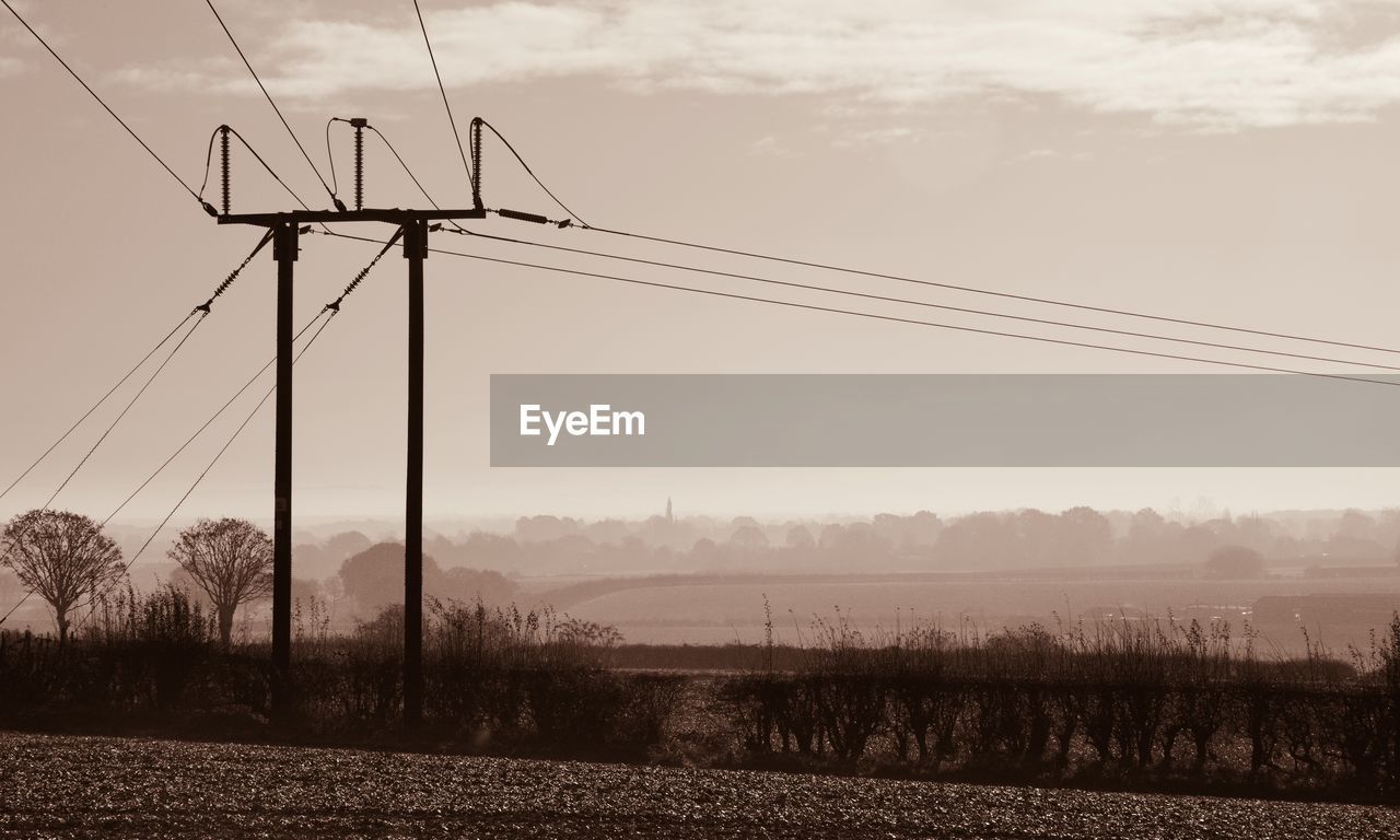ELECTRICITY PYLON ON FIELD AGAINST SKY DURING SUNSET