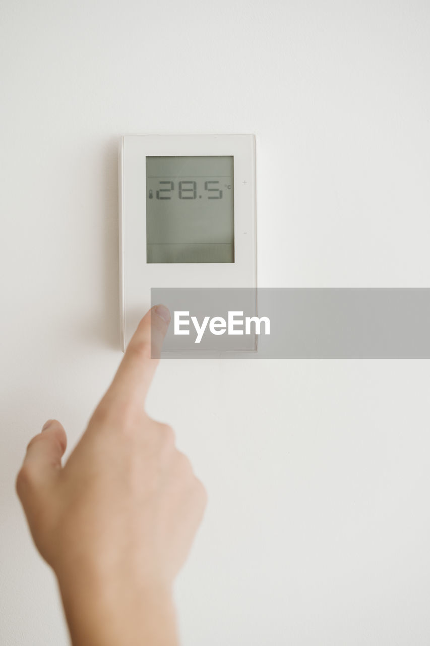 Finger touching thermostat on the wall