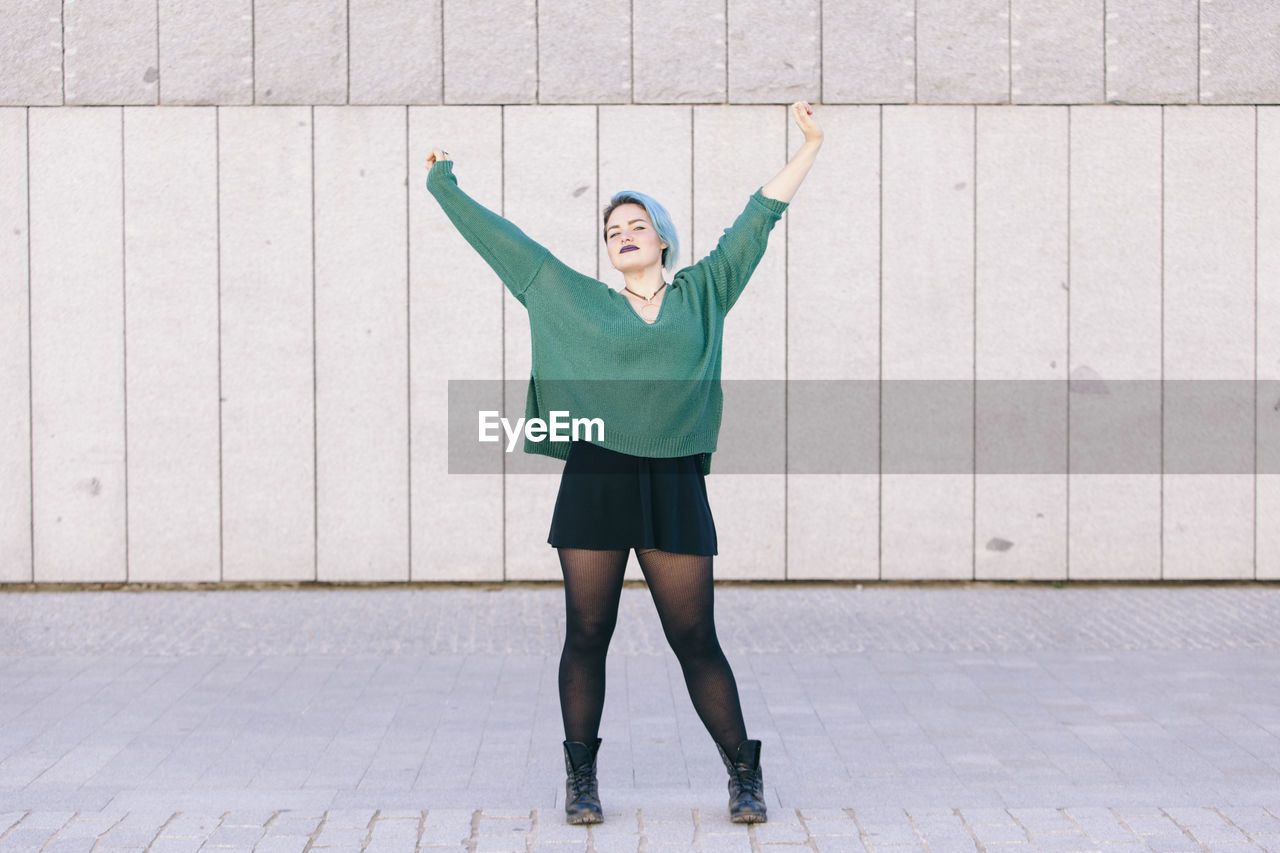 FULL LENGTH OF WOMAN STANDING AGAINST WALL