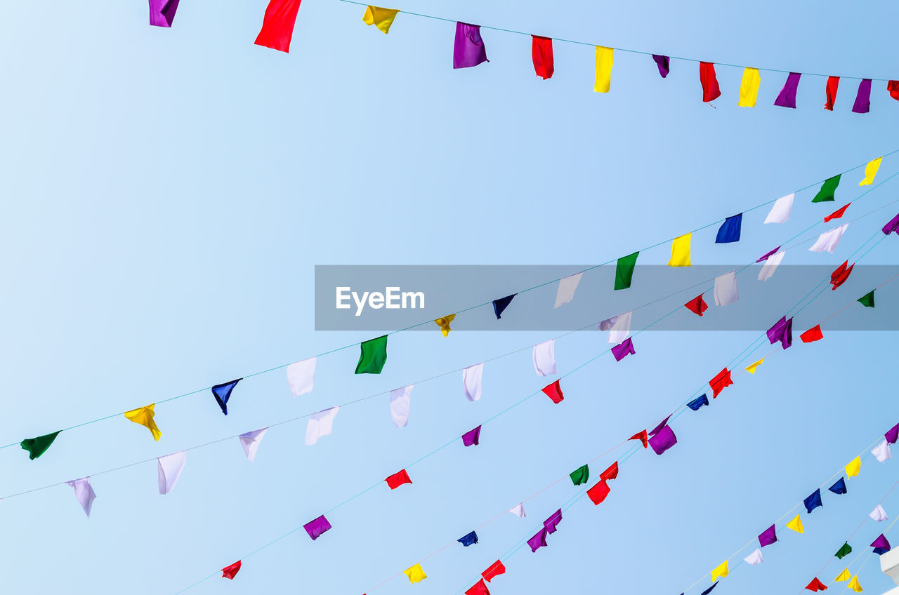 Low angle view of flags against clear blue sky